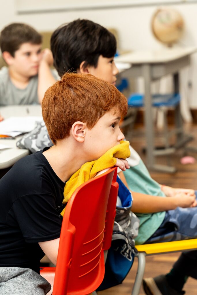Alunos em sala de aula conversando e aguardando o início das atividades