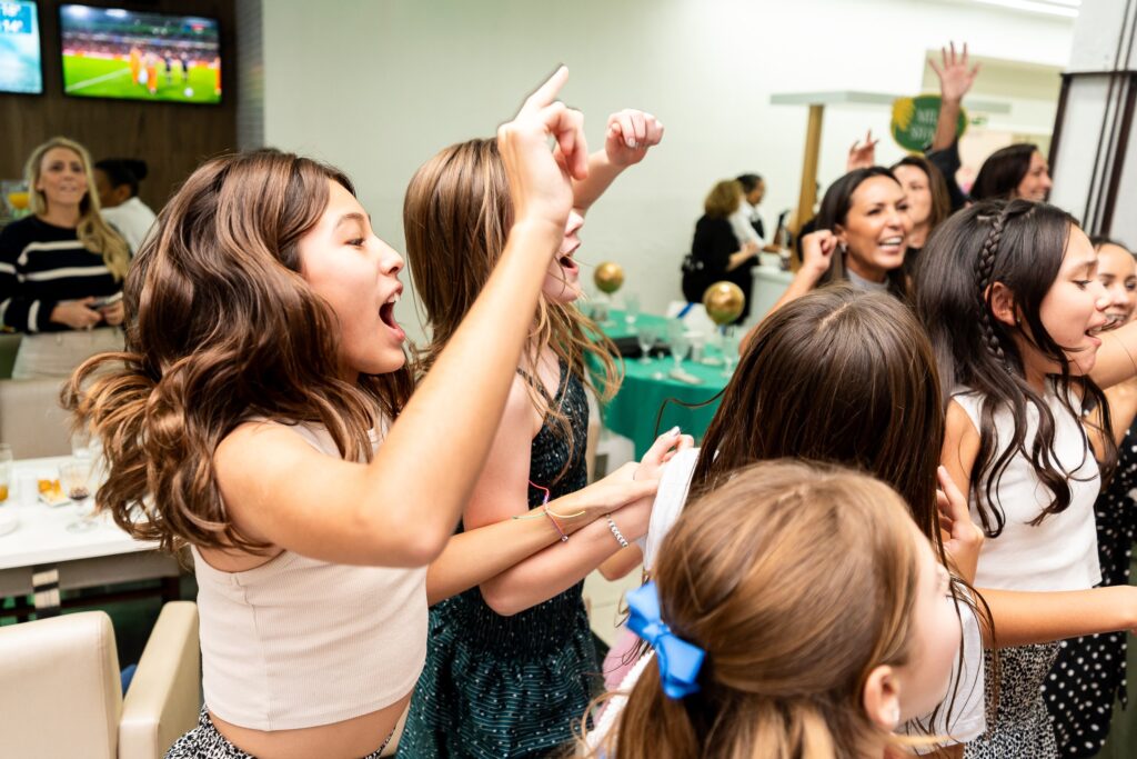 Crianças animadas comemorando durante a festa de formatura, com música, dança e decoração ao fundo